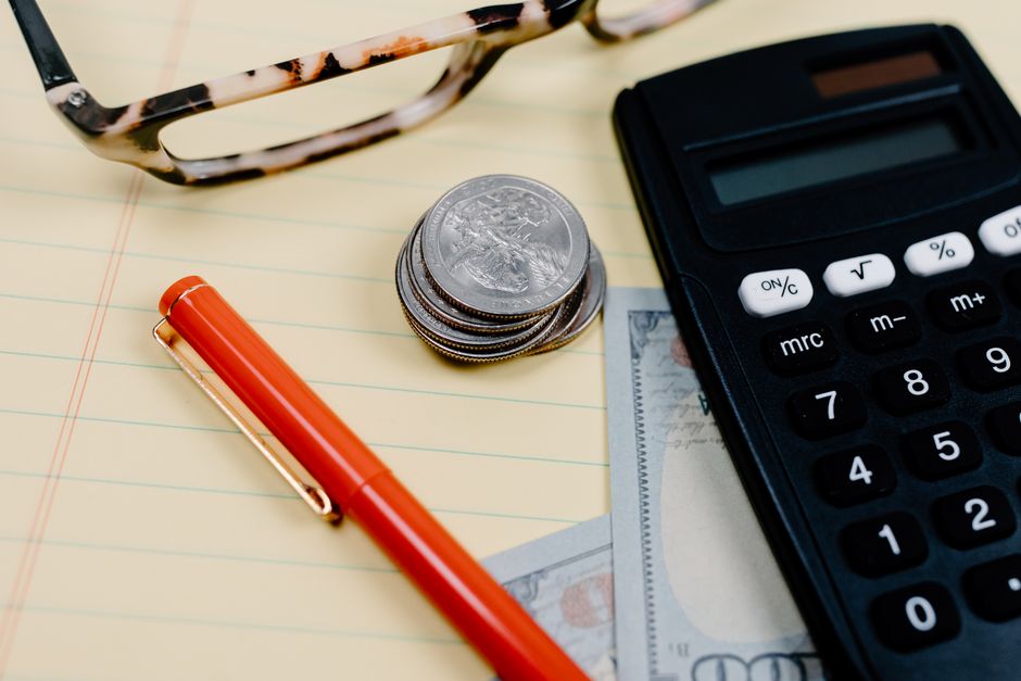 A minimalist, top-down view of a calculator and pen on an open notebook, symbolizing the cost breakdown and budgeting for a real estate license.