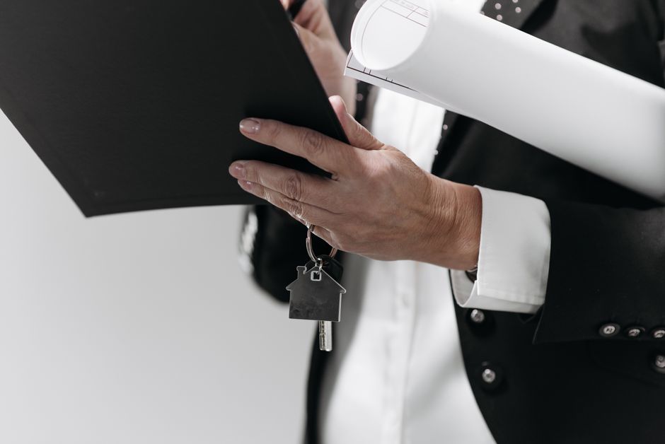A set of modern house keys rests on a professional wooden desk, representing the end goal and career outcome of investing in real estate education.