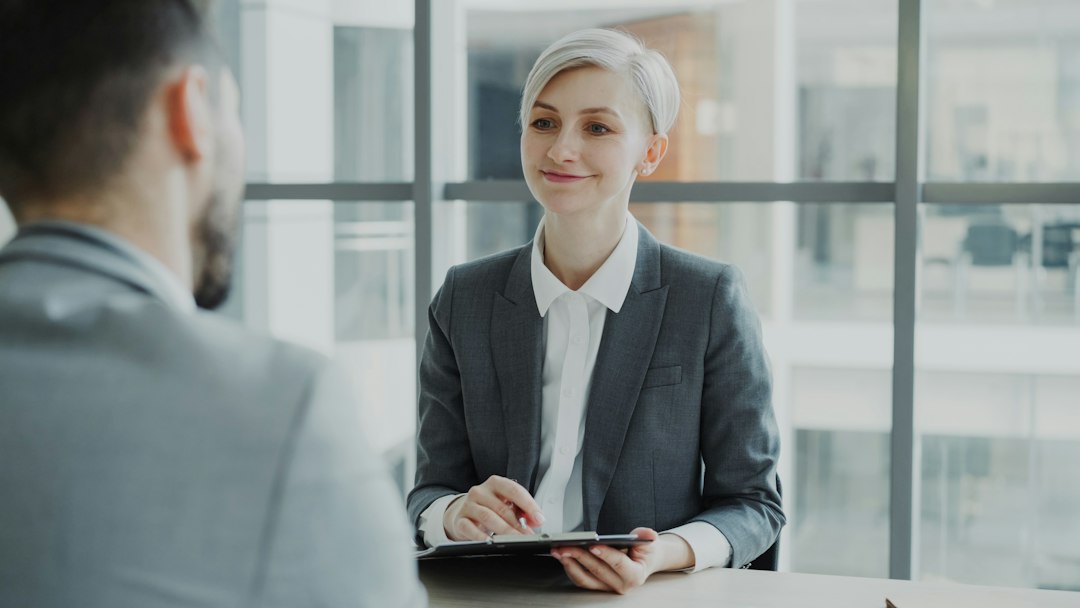 A lawyer and an insurance adjuster sit across from each other in a modern office, engaged in a serious and intense negotiation over a settlement.