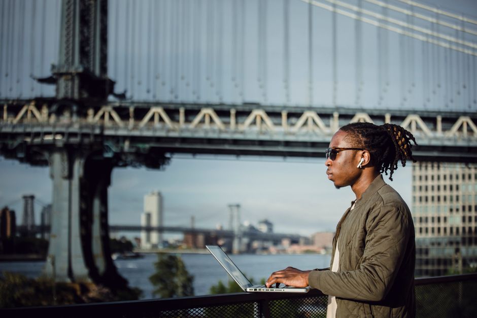 A professional working on a laptop from a classic New Orleans balcony with ironwork, symbolizing modern business in a historic city.